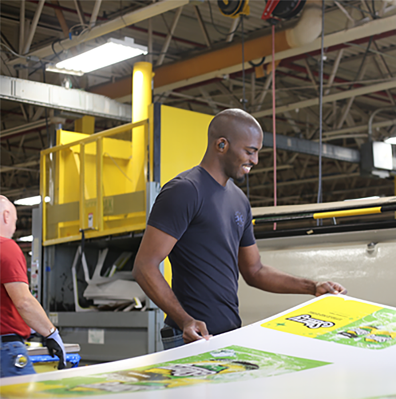 worker preparing the POP printed material to be cutout